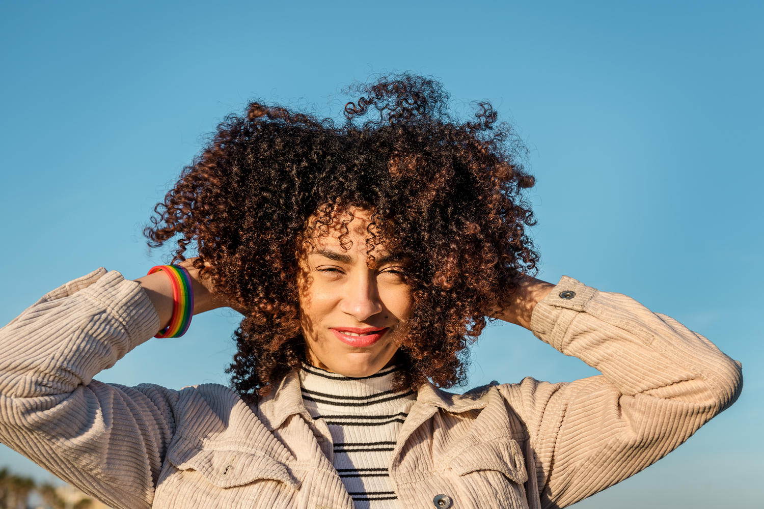 Frau mit Afrohaaren vor blauem Himmel