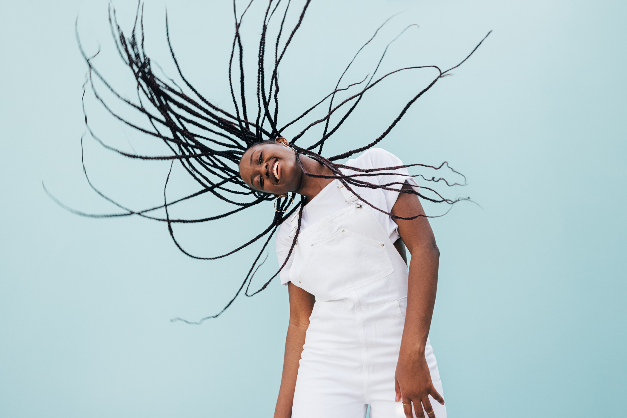 glückliche Frau mit Box Braids schüttelt ihr Haar