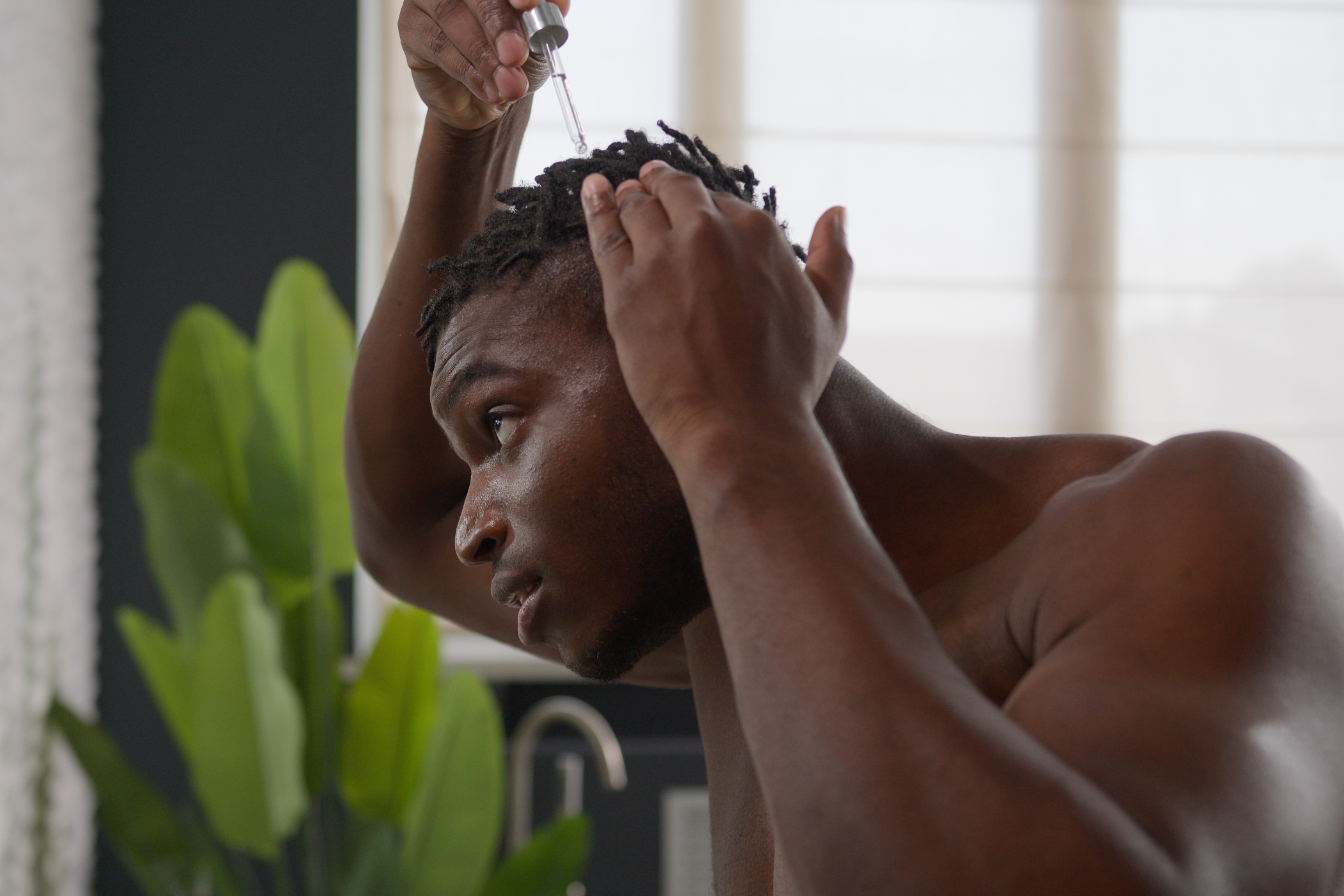 Mann macht Öl in seine Afrohaare