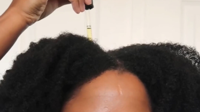 Tropfen Haaröl auf Afro-Kopfhaut